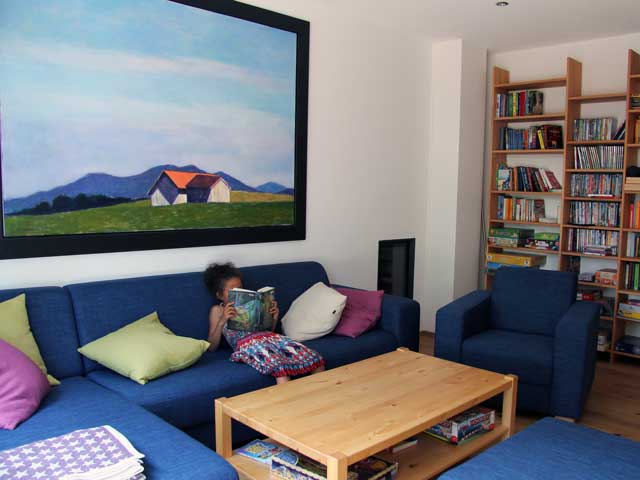 Blick in das Wohnzimmer des neuen „Haus südSee“ mit blauem Sofa. An der Wand ein Bild des Kunstmalers Reiner Wagner, das der südSee e. V. als Leihgabe erhielt
